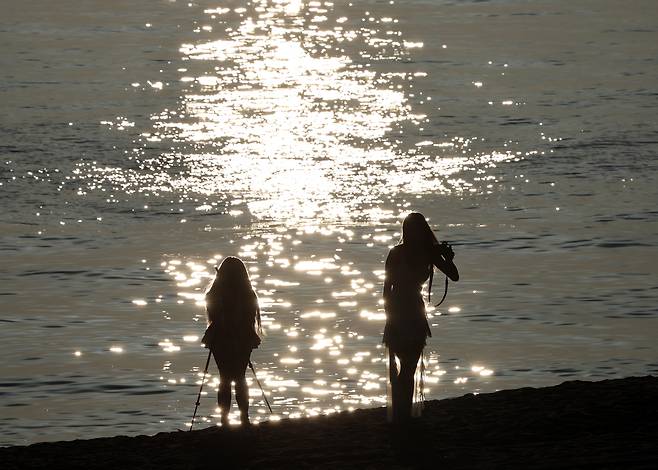 강원 강릉지역에 열대야가 계속된 21일 일출 시각 한껏 차려입은 동남아 관광객들이 경포해수욕장에서 추억을 남기는 사진을 찍고 있다.[연합]