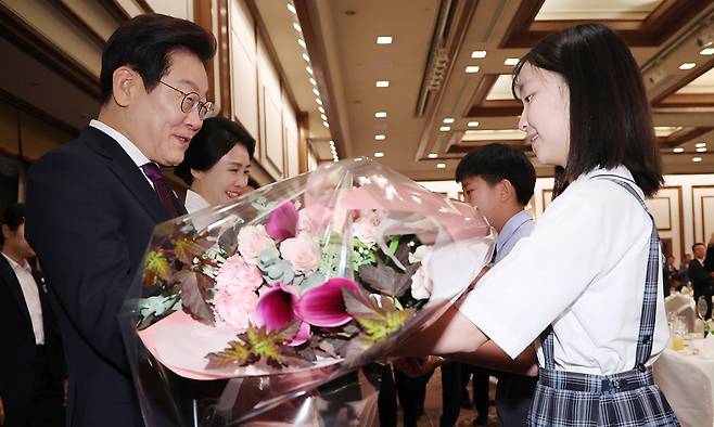 이재명 대통령과 김혜경 여사가 23일 일본 도쿄의 한 호텔에서 열린 재일동포 오찬 간담회에 참석해 화동으로부터 꽃다발을 받고 있다. 연합뉴스