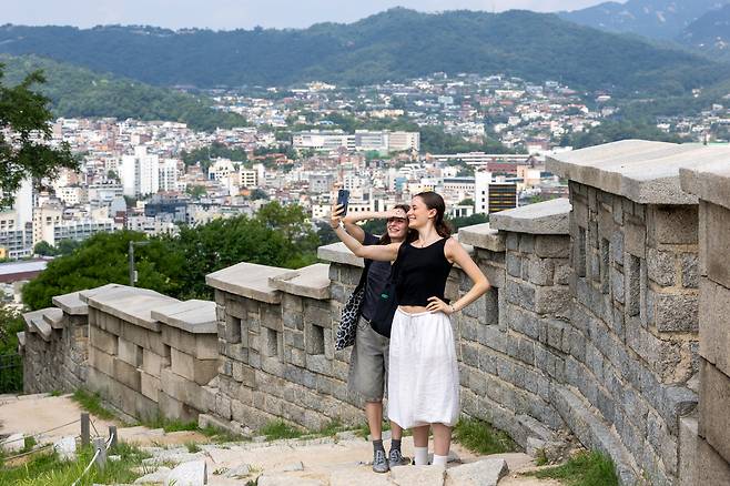 24일 서울 종로구 낙산공원 성곽길에서 외국인 관광객들이 소셜미디어에 올릴 ‘인증샷’을 찍고 있다. 넷플릭스 애니메이션 영화 ‘케이팝 데몬 헌터스’에서 주인공 루미와 진우가 데이트했던 장소다. 영화가 흥행하면서 낙산공원, 남산 서울타워 등 영화 속 서울 명소에 외국인 관광객이 몰리고 있다./김지호 기자