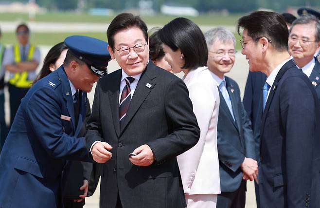 취임 후 처음 미국을 방문한 이재명 대통령이 24일(현지시간) 미국 워싱턴DC 인근 앤드루스 합동기지에 도착해 공군1호기에서 내려 영접 인사로 나온 미국 측 조슈아 킴 대령으로부터 기지 방문 기념 코인을 받아 들고 있다./연합뉴스