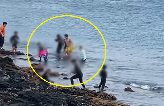 김원 순경(노란색 수영복)과 시민 2명(흰색 상의, 분홍색 튜브)이 구조한 40대 남성이 부축받으며 육지로 올라오는 모습. (제주해경서 제공)