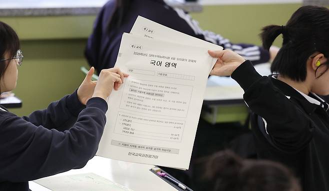 고등학교 3학년 학생들이 2026학년도 대학수학능력시험 6월 모의평가 1교시 국어 영역 문제지를 뒤로 전달하고 있다. /뉴스1