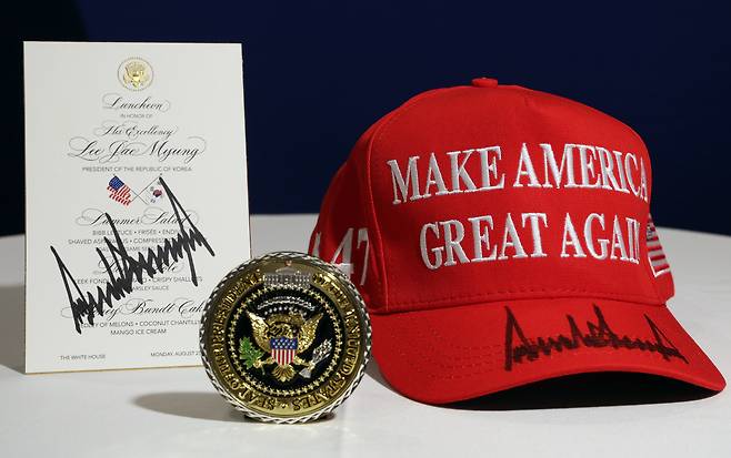 Gifts from U.S. President Donald Trump to Korean President Lee Jae Myung during their summit in Washington on Aug. 25 include a commemorative White House medal, a MAGA hat bearing Trump’s signature and a signed luncheon menu. [JOINT PRESS CORPS]