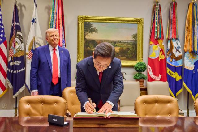 이재명 대통령이 25일(현지 시간) 미국 워싱턴 DC 백악관에서 도널드 트럼프 미국 대통령이 지켜보는 가운데 방명록을 작성하고 있다. 연합뉴스