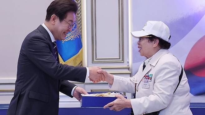 이재명 대통령이 여성 국가유공자 이춘자 참전용사에게 광목이불을 선물하고 있다 2025.6.27 [자료사진]