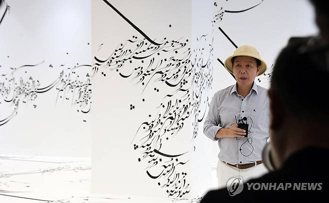 작품이 된 아랍어 (목포=연합뉴스) 형민우 기자 = 27일 전남 목포시 목포문화예술회관에서 2025 전남국제수묵비엔날레 프레스 오픈이 열려 윤재갑 전남국제수묵비엔날레 총감독이 파라스투 포로우 하르의 'Written Room'에 대해 설명하고 있다. 이 작품은 독일로 망명한 이란 출신의 작가가 아랍어로 전쟁과 폭력, 가부장제에 대한 비판을 담을 글을 먹으로 표현했다. 2025 전남국제수묵비엔날레는 30일부터 10월 31일까지 목포와 진도, 해남 등에서 '문명의 이웃들'을 주제로 다양한 수묵 작품을 선보인다. 2025.8.27 minu21@yna.co.kr