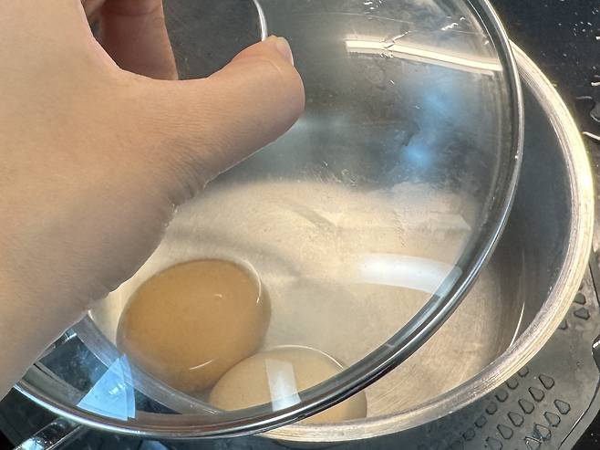 계란 2개가 들은 냄비 뚜껑을 닫는 모습