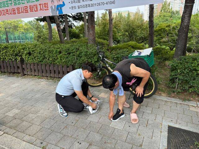 일산방주교회의 오시헌(왼쪽) 목사가 지난 2일 서울 영등포공원에서 폭우로 신발이 망가진 노숙인에게 새 운동화를 선물하고 있다. 교회 제공