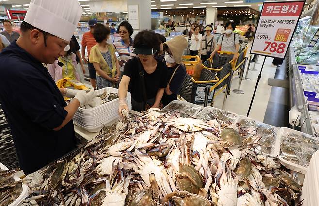 서울 한 대형마트를 찾은 고객이 해산물 판매대에서 꽃게를 고르고 있다.  [연합]