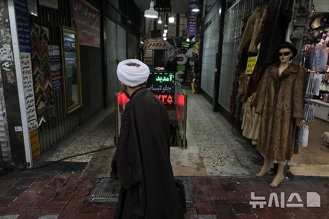 [테헤란(이란)=AP/뉴시스]지난 1월27일 이란 테헤란의 한 쇼핑센터 앞을 이란 성직자 1명이 지나가고 있다. 이란의 리알화가 28일 유럽 국가들이 이란의 핵 프로그램에 대한 유엔의 제재를 다시 부과, 그렇지 않아도 어려운 이란 경제를 더욱 압박할 것이라는 우려가 커지면서 거의 사상 최저치로 떨어졌다. 2025.08.28.