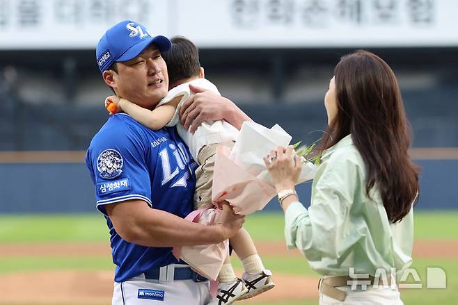 [서울=뉴시스] 권창회 기자 = 28일 서울 송파구 잠실야구장에서 KBO리그 두산 베어스와 삼성라이온즈의 경기 시작에 앞서 열린 오승환 은퇴투어 기념행사에서 삼성 오승환이 가족들로부터 꽃다발을 받고 있다. 2025.08.28. kch0523@newsis.com