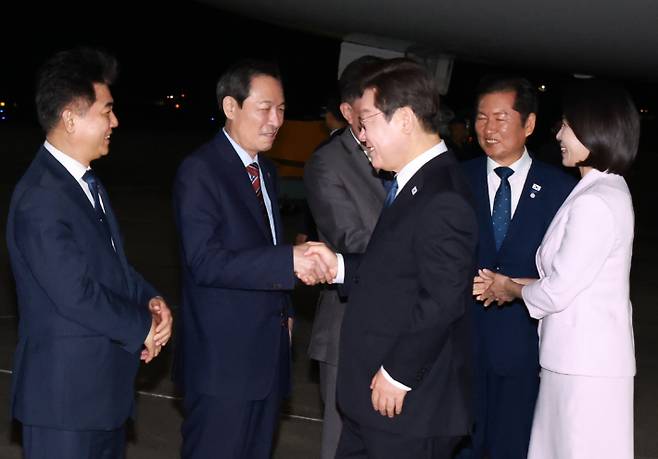 이재명 대통령과 김혜경 여사가 일본·미국 방문 일정을 마치고 28일 경기도 성남 서울공항에 도착해 영접 나온 우상호 정무수석과 인사하는 모습. 연합뉴스