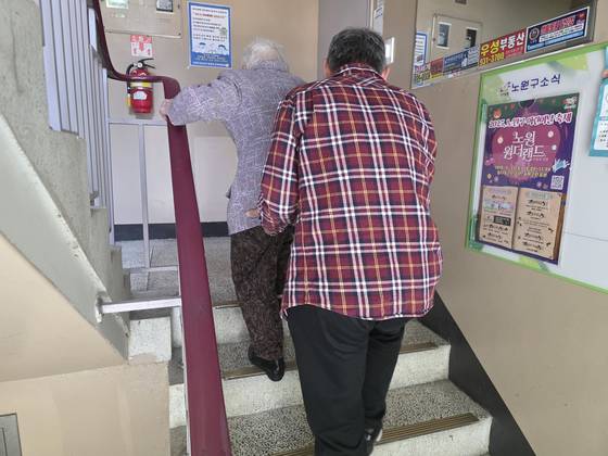 아들 김복희씨가 데이케어센터에서 돌아온 어머니를 부축해 3층 집으로 향하고 있다. 아들은 어머니의 등허리와 엉덩이를 받쳐 한 칸씩 계단을 올랐다. 김서원 기자