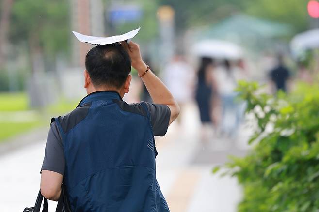 지난 8일 소나기가 내린 서울 세종대로에서 시민이 비를 막으며 이동하고 있다. [연합뉴스]