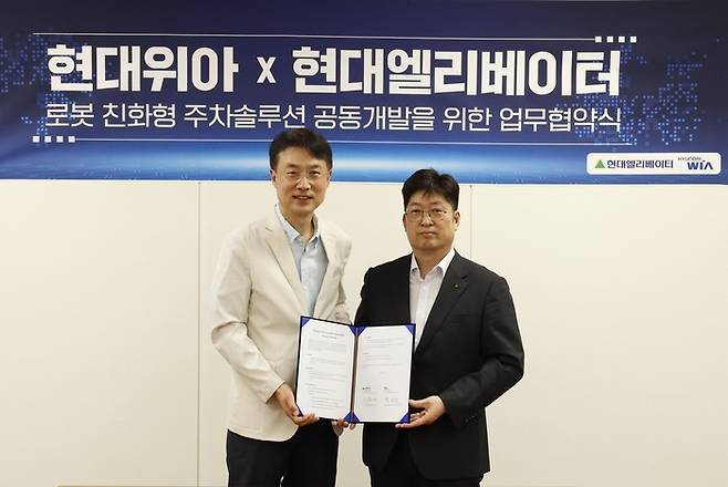 백익진 현대위아 모빌리티솔루션사업부 상무(왼쪽)와 이원해 현대엘리베이터 승강기사업본부장(상무)이 28일 경기도 의왕시 현대위아 의왕연구소에서 열린 ‘로봇 친화형 주차솔루션 공동개발을 위한 업무협약식’에서 기념 사진을 찍고 있다. <현대위아>