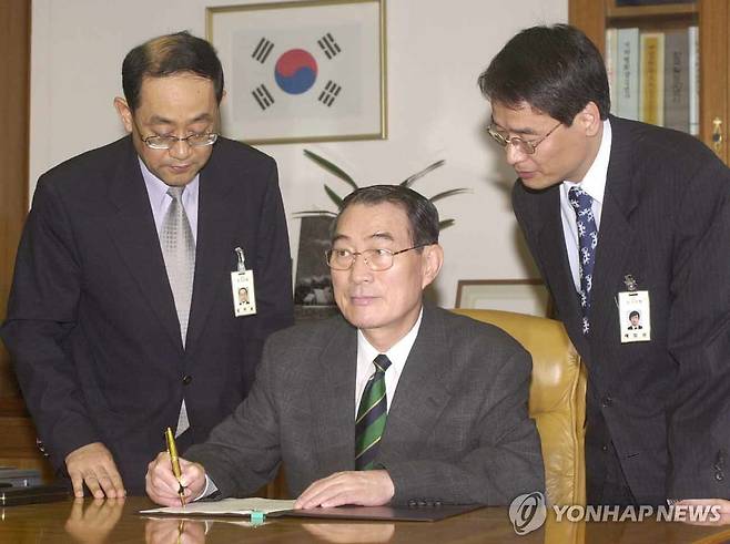 전철환 한은총재 IMF졸업 서명 (서울=연합뉴스) 한국은행 전철환총재가 2001년 8월 23일 오전 한국은행에서 김주훈 국제협력실장(좌)과 배일상 국제기구팀장(우)이 배석한 가운데 IMF신용인출잔액 최종상환서에 서명하고 있다. [연합뉴스 자료사진] 2025.8.29