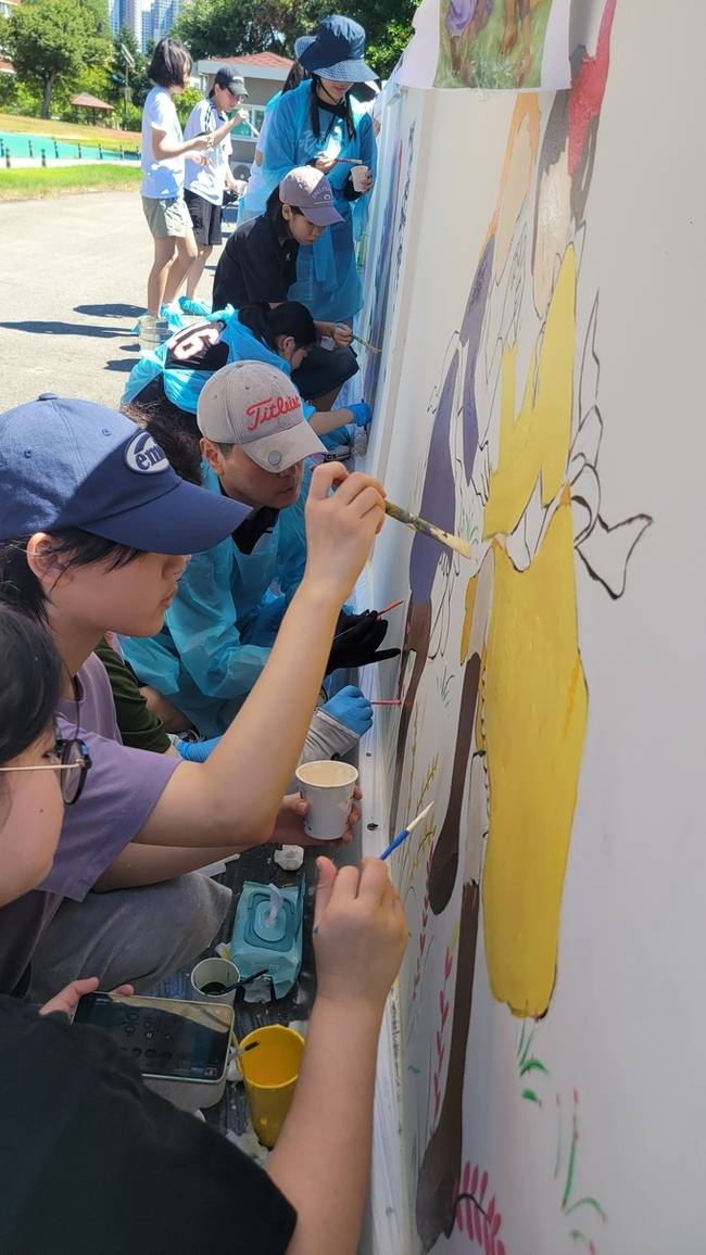 ▲ 윤종호 경북도의원이 초록별 아트스쿨 회원들과 구미여중 학생들이 합동으로 담장벽화를 그리고있다. 이봉한기자