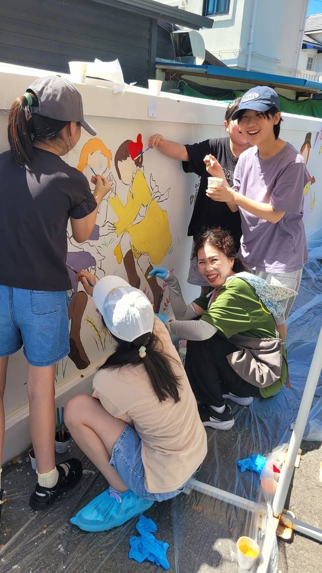 ▲ 구미여중 담장벽화를 그리면서 환하게 웃고있는 초록별 아트스쿨 회원과 학생들. 이봉한기자