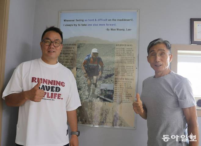이종민 대표(왼쪽)가 경기도 김포 회사 사무실에서 아버지 이무웅 씨와 함께 엄치척을 했다. 벽에  걸린 사진은 이무웅 씨가 사막을 달리는 모습. 김포=양종구 기자 yjongk@donga.com