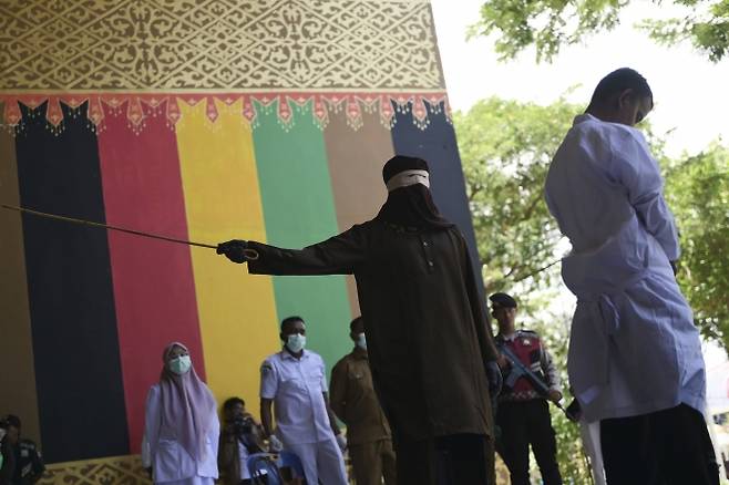 지난 26일(현지시간) 인도네시아 아체주 반다아체에서 태형 집행관이 공원 화장실에서 다른 남성과 키스해 샤리아(이슬람 율법)를 위반한 혐의로 유죄 판결을 받은 남성에게 등나무 지팡이로 매질을 하고 있다. 2025.8.26 AP 연합뉴스