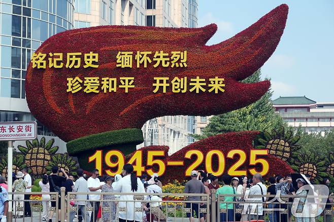 중국의 항일전쟁 및 세계 반파시스트 전쟁(제2차 세계대전) 승리 80주년(전승절) 기념 열병식을 사흘 앞둔 31일 중국 베이징 천안문 인근 거리에 설치된 꽃 조형물 앞에서 행인들이 기념 사진을 찍고 있다. 2025.8.31/뉴스1 ⓒ News1 박정호 기자