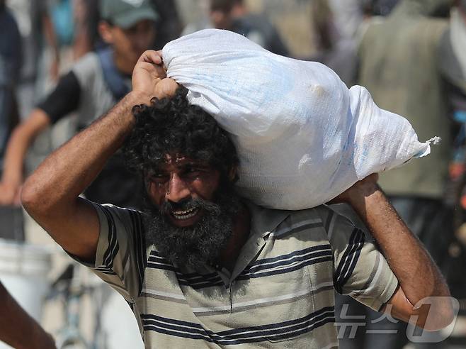 2025년 8월 1일 가자지구 북부 베이트라히아에서 한 팔레스타인 주민이 이스라엘을 통해 가자에 들어온 구호 물품이 담긴 가방을 들고 걷고 있다. 2025.8.1 ⓒ 로이터=뉴스1 ⓒ News1 강민경 기자