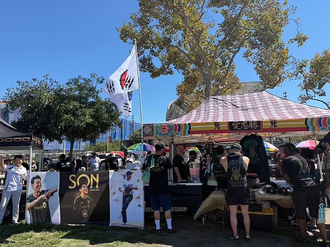 31일(현지 시각) 미 로스앤젤레스 BMO스타디움 인근 잔디밭에서 LAFC의 축구팬들이 경기 전 응원 행사를 갖고 있다. 태극기와 손흥민의 플래카드가 걸린 이 부스에선 한글과 손흥민 얼굴이 새겨진 각종 굿즈를 팔고 있었다./강다은 기자