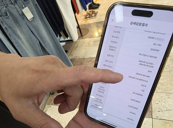 대전 중앙로지하상가에서 옷가게를 운영 중인 박명준(가명·38)씨가 지난해 5월 진행된 지하상가 공개경쟁입찰에서 자기 점포 결과가 나온 ‘온라인 입찰 시스템’(온비드) 모바일 애플리케이션 화면을 가리키고 있다. 최예린 기자 floye@hani.co.kr