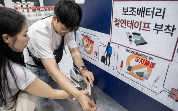 1일 김해국제공항 수하물 정리대에서 탑승객들이 보조배터리에 절연테이프를 붙이고 있다.   이원준 기자 windstorm@kookje.co.kr