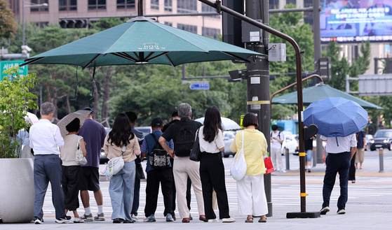 As sweltering heat continues, citizens wait under a shade canopy at a crosswalk in central Seoul on Aug. 21. [NEWS1]