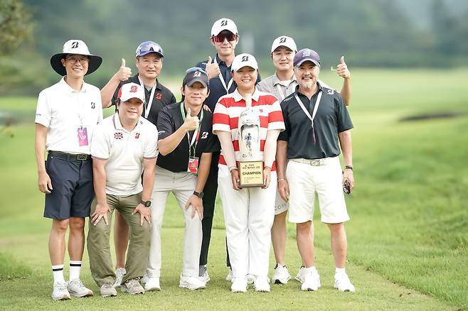 신다인(가운데)이 KLPGA 투어 KG 레이디스 우승컵을 들고 이민기(앞줄 맨 오른쪽) 석교상사 회장 등 임직원들과 기념 촬영을 하고 있다.    [석교상사 제공]