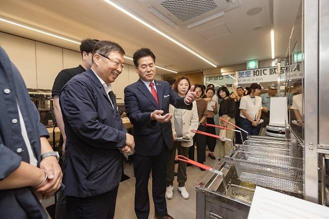 김경호(왼쪽 두 번째) 서울 광진구청장이 광진경제허브센터 입주기업인 헬퍼로보틱스으로부터 튀김로봇에 대한 설명을 듣고 있다.   광진구 제공