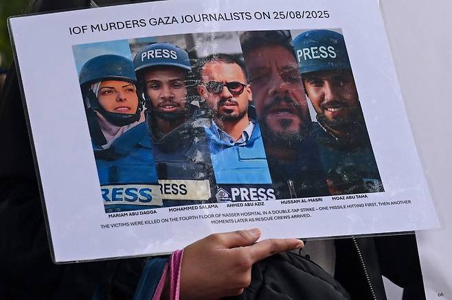 8월27일 영국 런던에서 열린 추모 집회에서 한 참석자가 8월25일 이스라엘 군의 공습으로 가자 지구 남부 나세르 병원에서 사망한 언론인들의 사진 피켓을 들고 있다. 왼쪽부터 마리암 아부 다가, 모하메드 살라마, 아흐메드 아부 아지즈, 후삼 알 마스리, 모아즈 아부 타하 기자. ⓒREUTERS