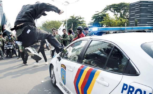 한 인도네시아 시민이 경찰차에 분노의 발길질을 날리고 있다. [사진=AP/연합뉴스]