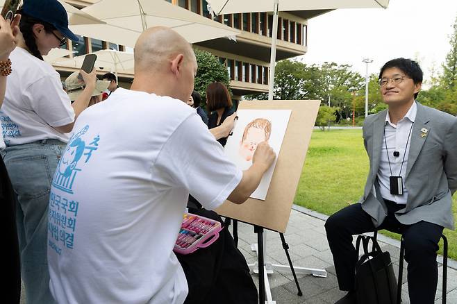A tattoo artist draws a caricature of liberal Democratic Party Rep. Park Ju-min, who introduced the so-called tattooist bill, at the National Assembly in western Seoul on Aug. 27. [NEWS1]