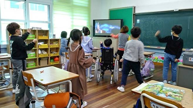 휠체어에 토도드라이브를 장착한 어린이가 친구들과 어울려 학습하는 모습 <토도웍스>