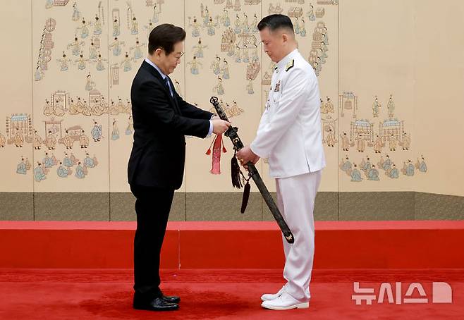 [서울=뉴시스] 최동준 기자 = 이재명 대통령이 2일 서울 용산 대통령실 청사에서 열린 대장 진급·보직 신고 및 삼정검 수치 수여식에서 강동길 해군참모총장의 삼정검에 수치를 달아주고 있다. (대통령실통신사진기자단) 2025.09.02. photocdj@newsis.com