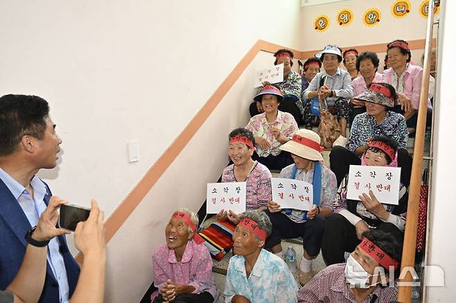 [광주=뉴시스] 박기웅 기자 = 13일 오후 광주 광산구 삼도동 행정복지센터 2층에 마련된 '광주시 자원회수시설(쓰레기 소각장) 설치사업 전략·기후환경평가 초안 주민설명회' 공청회장 입구를 삼도동 주민들이 점거, 공청회 개최를 반대하는 구호를 외치고 있다. 2025.08.13. pboxer@newsis.com