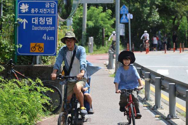▲대전 한낮 기온이 30도에 육박하며 더운 날씨를 보인 10일 대전 대덕구 대청댐 금강 종주 자전거길을 찾은 가족이 자전거를 타고 있다. ⓒ연합뉴스