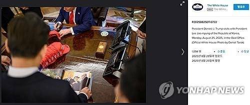 지난달 25일(현지시간) 미국 워싱턴DC 백악관 오벌오피스에서 열린 이재명 대통령과 도널드 트럼프 대통령의 한미 정상회담 당시 사진을 백악관이 최근 사진 공유 사이트를 통해 공개했다. 이재명 대통령이 트럼프 대통령 화보집을 보는 동안 트럼프 대통령이 마가 모자에 서명하고 있다. 2025.9.1 플리커 백악관 계정