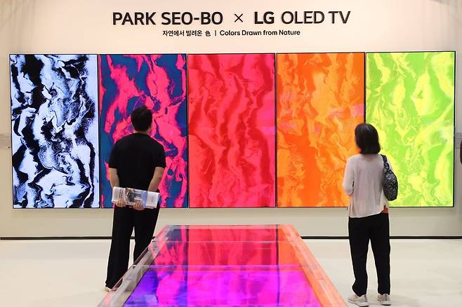 프리즈 서울 2025에서 선보인 LG OLED <자연에서 빌려온 색>전시 전경. 박제성 서울대 미대 교수 겸 미디어 아티스트가 AI로 재해석한 <자연의 시, 시의 색>을 관람객들이 바라보고 있다. /연합뉴스