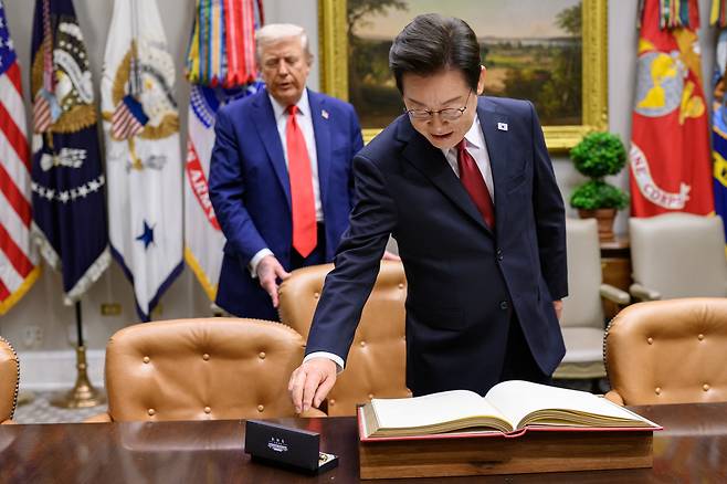 Korean President Lee Jae Myung, front, signs the guest book in the Roosevelt Room on Aug. 25 before a bilateral meeting with U.S. President Donald Trump. [THE WHITE HOUSE]