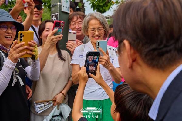 ▲ 시민들이 이재명 대통령 부부를 스마트폰으로 찍는 모습. 시민들의 웃는 표정이 살아있고 사진 프레임 속에서 또 다시 프레임이 발견되는 사진이다. 사진=대통령실