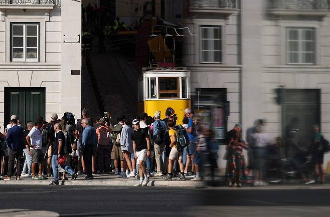 2025년 9월 4일, 포르투갈 리스본에서 발생한 글로리아 푸니쿨라 사고 다음 날, 보행자들이 잔해(사진에는 보이지 않음) 근처를 지켜보고 있다. 구조대원들에 따르면, 2025년 9월 3일 리스본에서 유명한 푸니쿨라가 탈선해 최소 17명이 숨지고 21명이 부상했다. [AFP 연합뉴스]