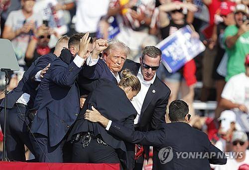 2024년 7월 13일(현지시간) 미국 펜실베이니아 버틀러 유세에서 총격을 당한 트럼프 전 대통령이 단상에서 내려오며 주먹을 머리 위로 쥐어 보이고 있다. 이 사진은 2021년 퓰리처상을 받은 에번 부치 AP 기자가 촬영했다. AP연합뉴스