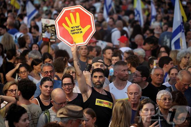 17일(현지시간) 이스라엘 텔아비브 '인질 광장' 일대에서 열린 인질 석방과 가자 전쟁 종식을 촉구하는 집회에서 한 참석자가 "네 아우의 핏소리가 땅에서부터 내게 호소하느니라＂라고 적힌 손팻말을 들고 있다. 2025.08.17. ⓒ 로이터=뉴스1 ⓒ News1 윤다정 기자