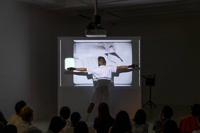 Artist Jimmy Robert performs “Éclipser (performance documentation)” at Barakat Contemporary in Jongno District, central Seoul, during Samcheong Night on Sept. 4. It features Theresa Hak Kyung Cha’s “Art Practice- The Sand Grain Story - Framed Text and Photo” (1977, 1980). [BARAKAT CONTEMPORARY /JIMMY ROBERT]
