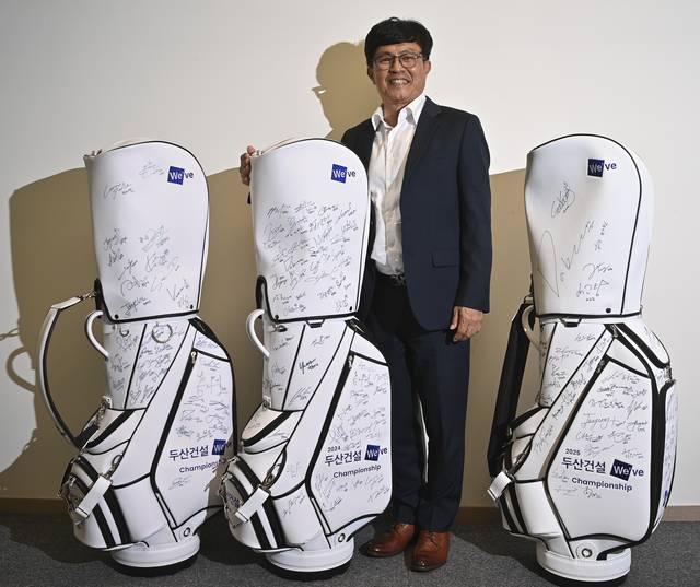 오세욱 두산건설 PR담당상무 겸 골프단장이 지난 2일 서울 강남구 두산빌딩 사무실에서 올해 4월 열린 두산건설 위브챔피언십에 참가한 선수들이 서명을 한 캐디백을 배경으로 포즈를 취하고 있다.  백동현 기자
