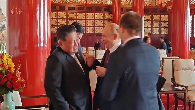 북한 조선중앙TV는 6일 김정은 국무위원장의 지난 2~4일 중국 방문을 담은 기록영화를 방영했다. 사진은 중앙TV가 공개한 김정은 위원장과 블라디미르 푸틴 러시아 대통령이 열병식 행사가 끝난후 만나서 대화하는 도중 파안대소하는 모습. [조선중앙TV 화면·연합]