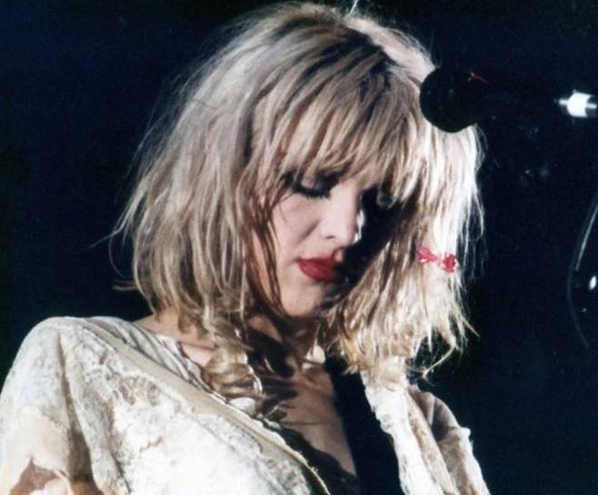 코트니 러브 주도의 밴드 홀(Hole)의 2집 ‘이걸 경험해봐’(Live Through This)는 펑크의 문법으로 펑크를 비웃는 자기수행과 자기해체의 구조를 전면에 세운 작품이다. 왕관, 레이스, 엉망으로 번진 립스틱 등 무대 위 과장된 자기전시는 ‘당신(대중과 미디어)들이 원하는 이미지’를 그대로 들이밀어 거울처럼 반사했고, 이를 목이 쉴 정도로 긁는 거친 보컬과 미세한 뒤틀림, 후렴에서의 과부하와 조합해 ‘진정성=자기소모’라는 공식을 재현하는 날카롭게 비웃었다. [게티이미지/Photo by Jim Steinfeldt·Michael Ochs Archives]